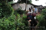 Anggota Polres Situbondo membopong warga korban angin kencang di Desa Kembangsari, Jatibanteng, Situbondo, Jawa Timur, Kamis (9/2). Polres Situbondo memperbaiki rumah warga, menyalurkan bantuan berupa mie instan, sembako, obat-obatan dan pemeriksaan kesehatan gratis bagi korban angin kencang. Antara Jatim/Seno/zk/17