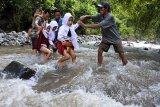 Sejumlah siswa SDN 1 Campoan dibantu guru dan warga menyeberangi sungai di Desa Campoan, Mlandingan, Situbondo, Jawa Timur, Selasa (7/2). Sejumlah siswa setiap hari menyeberangi sungai untuk menuju sekolah karena jembatan penghubung menuju sekolah rusak diterjang banjir. Antara Jatim/Seno/zk/17