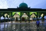 Warga berjalan menuju masjid di kampung Sumber Langgeng yang terendam air di Kawasan Sumber Rejo, Surabaya, Jawa Timur, Minggu (5/2). Sejumlah perkampungan di kawasan tersebut sampai saat ini terendam air akibat tanggul anak sungai Kali Lamong yang jebol pada hari Sabtu (4/2). Antara Jatim/Didik Suhartono/zk/17