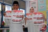 Calon Gubernur Aceh Tarmizi Karim (kiri) dan Istri memperlihatkan surat suara sebelum memberikan suara di TPS 5 Lamprit, Banda Aceh, Aceh, Rabu (15/2). Pasangan calon Gubernur/Wakil Gubernur Aceh periode 2017-2022 Tarmizi Karim/T Machsalmina Ali diusung partai Golkar, Nasdem, PPP, PKPI dan Hanura pada pilkada serentak. (ANTARA FOTO/Irwansyah Putra)