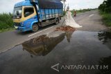 Pengendara truk melintas di jalur utama menuju kawasan wisata monumen Simpang Lima Gumul (SLG) yang rusak di Desa Ngasem, Kediri, Jawa Timur, Kamis (16/2). Jalur menuju wisata andalah Kediri tersebut membahayakan pengguna jalan karena banyaknya lubang berukuran besar di sejumlah titik akibat sering dilalui kendaraan angkutan barang melebihi ambang batas tonase. Antara Jatim/Prasetia Fauzani/zk/17