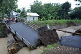 Sejumlah warga melihat kondisi jembatan yang roboh di Desa Margomulyo Kecamatan Panggungrejo, Blitar, Jawa Timur, Minggu (12/2). Jembatan yang menghubungkan dua desa tersebut roboh akibat diterjang arus air sungai yang volumenya meningkat karena curah hujan yang tinggi didaerah tersebut dalam beberapa hari terakhir. Antara Jatim/Irfan Anshori/zk/17