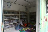 Warga membaca buku di dalam Taman Baca Masyarakat (Tabamas) yang terbuat dari kontainer bekas di Alun-alun Nganjuk, Jawa Timur, Sabtu (18/2). Perpustakaan mini yang menyediakan ribuan judul buku secara gratis tersebut bertujuan mempermudah warga mendapatkan bahan bacaan bermutu guna mendongkrak minat baca masyarakat. Antara Jatim/Prasetia Fauzani/zk/17