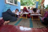 Seorang guru mengajar sejumlah siswa di teras atau halaman sekolah di SDN Biting 4 Kecamatan Arjasa, Kabupaten Jember, Jawa Timur, Senin (20/2). Puluhan siswa kelas 1 dan 2 SDN Biting 4 terpaksa belajar dengan cara lesehan di teras sekolah karena ruang kelas di sekolah setempat rusak parah. Antara Jatim/Zumrotun Solichah/zk/17
