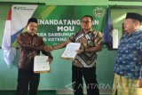 Ketua SARBUMUSI NU Blitar H. Aspandi menyerahkan Memorandum Of Underatanding (MOU) kepada Kepala Cabang BPJS Ketenagakerjaan Blitar Oki W. Gandha usai penandatanaganan MOU di Blitar, Jawa Timur, Jumat (24/2). Antara Jatim/Irfan Anshori/Zk/17