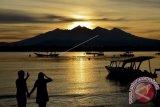 Sepasang wisatawan memperhatikan siluet Gunung Rinjani saat 'Sunrise' (matahari terbit) di pinggiran pantai Gili Trawangan, Desa Gili Indah, Kecamatan Pemenang, Tanjung, Lombok Utara, NTB, Jumat (24/2). Gili Trawangan adalah satu dari tiga pulau kawasan wisata Gili Matra (Gili Meno, Gili Air dan Gili Trawangan) yang ramai dikunjungi wisatawan domestik dan mancanegara sepanjang tahun. ANTARA FOTO/Ahmad Subaidi/wdy/17