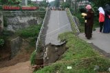 Warga mengamati jembatan jalur utama Kediri-Tulungagung yang roboh di Desa Ngadi, Kediri, Jawa Timur, Selasa (28/2). Jembatan berusia empat tahun tersebut roboh karena derasnya debit air sungai Jugo sehingga warga harus memutar sejauh 5 km melewati jalur altenatif bila hendak menuju Kediri ke Tulungagung ataupun sebaliknya. ANTARA FOTO/Prasetia Fauzani/pd/17