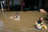 Dua orang anak bermain air di halaman rumah yang terendam banjir di Desa Janti Kapur, Kediri, Jawa Timur, Kamis (2/3). Banjir yang merendam tiga desa di wilayah tersebut akibat meluapnya sungai Bogokerep dan Sungai Kolokoso. Antara jatim/Prasetia Fauzani/zk/17