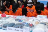 Sejumlah barang bukti dan tersangka ditunjukkan saat pemusnahan barang bukti narkoba di Polda Jawa Timur, Kamis (2/3). Barang bukti hasil ungkap Polda Jatim yaitu Shabu seberat 32,326 kilogram, Ganja seberat 41,298 kilogram, pil ekstasi sebanyak 12.418 butir, pil Happy Five sebanyak 170 butir dan obat keras daftar G sebanyak 25.231 butir sedangkan hasil ungkap BNNP Jatim Shabu seberat 3,541 kilogram dan Ganja sekitar 9 kilogram tersebut dimusnahkan. Antara Jatim/Didik Suhartono/zk/17