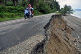 Pengendara melintas di jalan yang rusak akibat abrasi pantai di Desa Enu, Kabupaten Donggala, Sulawesi Tengah, Minggu (5/3). Menurut warga setempat, abrasi pantai itu terjadi sejak beberapa bulan terakhir dan terus mengikis jalur Trans Sulawesi yang menghubungkan Kota Palu dan Kabupaten Donggala serta Kabupaten Tolitoli tersebut. ANTARA FOTO/Mohamad Hamzah/pd/17.