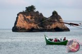 Perahu nelayan melintas di dekat batu legenda yang dikenal dengan sebutan batu Amat Ramanyang di Krueng Raya, Aceh Besar, Aceh, Minggu (12/3). Cerita tentang batu legenda Amat Ramanyang tidak berbeda dengan cerita Malin Kundang yakni anak durhaka yang dikutuk perahu menjadi batu dan kini menjadi salah satu objek wisata di Provinsi Aceh. (ANTARA FOTO/Irwansyah Putra)