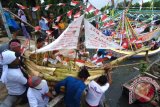 Nelayan menggotong miniatur perahu berisi sesaji ketika akan dilarung dalam pesta Petik Laut di Pantai Desa Kaduara Timur, Sumenep, Jawa Timur, Rabu (15/3). Selain melestarikan budaya warisan leluhur, upacara tersebut juga dimaksudkan untuk mendapatkan keselamatan dan tangkapan ikan melimpah ketika melaut. ANTARA FOTO/Saiful Bahri/wdy/17.