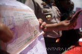 Petugas kepolisian menunjukkan barang bukti kwuitansi hasil pungutan liar yang dilakukan oleh kepala desa saat gelar rilis di Polresta Sidoarjo, Jawa Timur, Jumat (17/3). Satreskrim dan Tim Saber Pungli Polres Sidoarjo berhasil mengungkap kasus pungutan liar dalam pengurusan setifikat tanah dengan barang bukti kwuitansi  hasil pemungutan liar sebesar Rp250 juta yang dilakukan oleh kepala desa Semambung, Sidoarjo. Antara Jatim/Umarul Faruq/zk/17