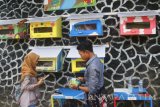 Pengunjung membaca di perpustakaan yang memanfaatkan kandang burung dara (pagupon) sebagai rak buku di Kampung Warna-warni, Jodipan, Malang, Jatim, Selasa (21/3). Perpustakaan tersebut sengaja didirikan untuk menumbuhkan minat baca masyarakat sekaligus mengenalkan pemanfaatan barang bekas pada para pengunjung. Antara Jatim/Ari Bowo Sucipto/zk/17.