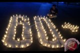 Warga menyalakan lilin membentuk angka 60 plus saat peringatan Earth Hour di kawasan Kuta, Bali, Sabtu (25/3). Aksi Earth Hour dengan mematikan lampu dan pada pukul 20.30 hingga 21.30 waktu setempat yang dilakukan di berbagai belahan dunia dilakukan sebagai bentuk kepedulian terhadap kondisi bumi sekaligus sebagai kampanye untuk menghemat pemakaian listrik. ANTARA FOTO/Fikri Yusuf/wdy/17.