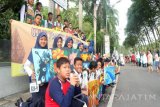 Sejumlah siswa SMP Negeri 2 Bojonegoro, Jawa Timur, memegangi lukisan di tepi jalan alun-alun kota yang menjadi ajang 'car free day' (CFD), Minggu. Sebanyak 256 siswa kelas 9 itu mengikuti kegiatan pameran untuk praktik evaluasi belajar tahap akhir (Ebta) di sekolahan setempat. Antara Jatim/Foto/Slamet Agus Sudarmojo/zk/16. 