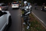 Seorang pengamen mengenakan kostum Robocop saat mengamen di kawasan Jalan Juanda, Depok, Jawa Barat, Kamis (30/3). Mengamen menggunakan kostum Robocop tersebut dilakukan Rusdi untuk menarik perhatian warga yang melintas. ANTARA FOTO/Indrianto Eko Suwarso/aww/17.