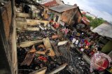 Warga melihat puing bangunan bekas kebakaran di permukiman nelayan, Desa Pusong Lama, Lhokseumawe, Aceh, Kamis (6/4). Kebakaran yang terjadi Rabu malam (5/4) itu diketahui akibat api lilin dari salah satu rumah saat pemadaman listrik bergilir, yang kemudian membakar sembilan rumah semi permanen, akibatnya 12 KK keluarga nelayan mengungsi. (ANTARA FOTO/Rahmad)