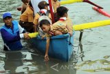 Seorang anak bermain air dari atas perahu saat Festival Kali Bersih di sungai Durahman, Banyuwangi, Jawa Timur, Sabtu (8/4). Pemerintah Daerah setempat menggelar Festival tersebut guna mengkampanyekan kebersihan sungai yang diharapkan mampu meminimalisir sampah mengalir ke laut. Antara Jatim/Budi Candra Setya/zk/17.