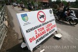 Warga melintas di atas jembatan Tambibendo yang dipasangi garis polisi di Desa Tambibendo, Kediri, Jawa Timur, Sabtu (8/4). Jembatan menuju kabupaten Tulungagung yang dibangun pada tahun 2001 tersebut terpaksa dipasangi garis polisi dan diberlakukan jalur searah bergantian karena kondisinya membahayakan. Antara Jatim/Prasetia Fauzani/zk/17