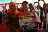 Menteri Sosial Khofifah Indar Parawansa (kiri) menyerahkan beasiswa kepada pelajar berprestasi saat penyaluran bantuan sosial nontunai Program Keluarga Harapan (PKH) di Alun-alun Kota Madiun, Jawa Timur, Senin (17/4). Kementerian Sosial menyalurkan bantuan sosial nontunai Program Keluarga Harapan (PKH) kepada 1.922 Keluarga Penerima Manfaat (KPM) di Kota Madiun sebesar Rp1.890.000 per KPM yang diterimakan empat kali selama 2017. Antara Jatim/Siswowidodo/zk/17