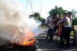 Petugas kepolisian berusaha memadamkan api saat penutupan jalan tol Reformasi di Makassar, Sulawesi Selatan, Senin (17/4). Aksi tersebut disebabkan belum terbayarkannya sisa ganti rugi lahan tahap II kepada ahli waris Intje Koemala binti Chandra Taniwijaya senilai Rp9 miliar lebih oleh Kementerian Pupera selama 16 tahun. ANTARA FOTO/Darwin Fatir/pras.