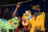 Penjual menata barongsai mainan di kawasan Tempat Ibadah Tri Dharma (TITD) Hwie Ing Kiong Madiun, Jawa Timur, Selasa (18/4). Penjual asal Semarang Jawa Tengah tersebut memanfaatkan momen hari jadi ke-130 TITD Hwie Ing Kiong dengan menjual barongsai mainan yang dijual dengan harga Rp50 ribu hingga Rp185 ribu perbuah tergantung ukuran dan kualitas. Antara Jatim/Siswowidodo/zk/17