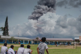 Sejumlah siswa bermain di halaman sekolah dengan latar belakang Gunung Sinabung yang mengeluarkan material vulkanik, di desa Ndokum Siroga, Karo, Sumatera Utara, Selasa (11/4). Gunung Sinabung berstatus Awas (level IV) sejak beberapa pekan terakhir, ditandai dengan erupsi dan luncuran awan panas yang semakin meningkat. ANTARA FOTO/Tibta Peranginangin/im/ama/17