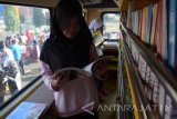 Pengunjung membaca buku di dalam mobil pintar di areal Car Free Day (CFD) Kota Madiun, Jawa Timur, Minggu (6/5). Mobil pintar milik Dinas Perpustakaan dan Kearsipan Kota Madiun yang sering beropasi di areal CFD tersebut sedikitnya dikunjungan 100 pembaca selama dua jam pelaksanaan CFD. Antara Jatim/Foto/Siswowidodo/zk/17