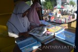 Pengunjung membaca buku di dalam mobil pintar di areal Car Free Day (CFD) Kota Madiun, Jawa Timur, Minggu (6/5). Mobil pintar milik Dinas Perpustakaan dan Kearsipan Kota Madiun yang sering beropasi di areal CFD tersebut sedikitnya dikunjungan 100 pembaca selama dua jam pelaksanaan CFD. Antara Jatim/Foto/Siswowidodo/zk/17