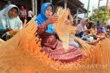 Warga menganyam bambu bersama-sama disepanjang jalan Desa Gintangan, Banyuwangi, Jawa Timur, Jumat (12/5). Kegiatan tersebut bagian dari agenda Banyuwangi Festival 2017 untuk mengangkat potensi kerajinan bambu di daerah itu. Antara Jatim/Budi Candra Setya/zk/17.
