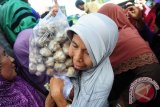 Seorang warga membawa bungkusan berisi Bawang Putih yang dibelinya saat gelar pasar murah di Pasar Flamboyan, Pontianak, Kalbar, Selasa (30/5). Guna menstabilkan harga Bawang Putih yang telah mencapai Rp100 Ribu per kilogram, Kementerian Perdagangan bersama Kementerian Pertanian dan Pemerintah Kota Pontianak mendistribusikan 60-100 Ton Bawang Putih yang dijual ke masyarakat seharga Rp30 Ribu per kilogram. ANTARA FOTO/Jessica Helena Wuysang/17
