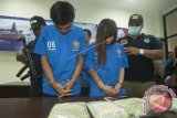 Petugas Badan Narkotika Nasional (BNN) menggiring dua tersangka kurir narkoba Steffani (kedua kanan) dan Sukron (kiri) beserta barang bukti ekstasi saat konferensi pers di Kantor BNN Provinsi Bali, Denpasar, Jumat (9/6). BNNP Bali menangkap Steffani setibanya di Bandara Ngurah Rai dari Palembang dengan membawa 9.675 butir ekstasi dan Sukron sebagai penerima narkoba itu di Denpasar. ANTARA FOTO/Nyoman Budhiana/wdy/17.