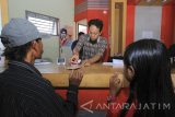 Nasabah melakukan proses pengambilan uang di Kantor Pos Muncar, Banyuwangi, Jawa Timur,Jumat (9/6). Kiriman uang dari tenaga kerja Indonesia (remitansi) yang dikirim kekeluarganya melalui kantor pos di Banyuwangi mencapai Rp1,2 miliar per hari atau naik sekitar 25 persen dari biasanya dan diprediksi akan terus naik sekitar Rp2 miliar per hari pada H-7 lebaran.. Antara Jatim/Budi Candra Setya/zk/17. 