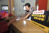 Seorang nasabah melakukan proses pengambilan uang di Kanntor Pos Muncar, Banyuwangi, Jawa Timur,Jumat (9/6). Kiriman uang dari tenaga kerja Indonesia (remitansi) yang dikirim ke keluarganya melalui kantor pos di Banyuwangi mencapai Rp1,2 miliar per hari atau naik sekitar 25 persen dari biasanya dan diprediksi akan terus naik sekitar Rp2 miliar per hari pada H-7 lebaran.. Antara Jatim/Budi Candra Setya/zk/17. 