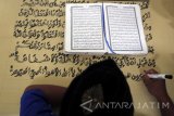  Seorang warga binaan bernama Ahmad Yani menulis mushaf (lembaran) Alquran raksasa di Lapas Klas IIB Blitar, Jawa Timur, Selasa (13/6). Kitab suci Alquran yang memiliki ukuran halaman 90 x 120 centimeter dengan tulisan tangan tersebut, ditargetkan rampung pada lima bulan mendatang. Antara Jatim/Irfan Anshori/zk/17 