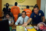 Wakil Direktur Reskrimsus Polda Bali, AKBP Rudi Setiawan (tengah) menunjukkan barang bukti dan tersangka hasil operasi tangkap tangan (OTT) korupsi pegawai negeri sipil Dinas Penanaman Modal Kabupaten Gianyar saat gelar perkara di Mapolda Bali, Sabtu (17/6). Tim gabungan meringkus dua orang tersangka yakni Kepala Dinas Penanaman Modal Kabupaten Gianyar berinisial IKM dan Kabid Perijinan dan Non Perijinan berinisial INS besarta barang bukti uang tunai senilai Rp14.450.000 hasil pemerasan terhadap korban yang sedang mengurus ijin. ANTARA FOTO/Wira Suryantala/wdy/17.