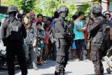 Personel Brimob berjaga saat diakukkannya penggeledahan di kediaman terduga teroris berinisial ATM di kawasan Tanah Merah, Surabaya, Jawa Timur, Senin (19/6). Sejumlah kardus yang diduga berisi barang bukti diamankan dalam penggeledahan tersebut. Antara Jatim/Didik Suhartono/zk/17