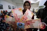 Warga menunjukkan uang saat pembagian zakat mal di Lhokseumawe, Aceh, Kamis (22/6). Pemerintah setempat melalui Baitul Mal menyalurkan bantuan dana zakat sebesar 1,4 miliar kepada 2.040 fakir dan miskin dari 68 desa di kota itu. (ANTARA FOTO/Rahmad)