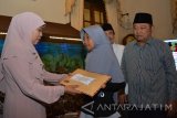 Menteri Sosial Khofifah Indar Parawansa (kiri) memberi santunan kepada korban meninggal akibat perahu tambang tenggelam disaksikan bupati Sidoarjo Saiful illah (kanan) di Pendopo Sidoarjo, Jawa Timur, Jumat (23/6). Sebanyak 8 ahli waris atau keluarga korban meninggal dalam bencana perahu tambang yang tenggelam di Sungai Kalimas, Wringinanom, Gresik, 13 April 2107 menerima santunan tunai Rp15 juta. Antara Jatim/Umarul Faruq/zk/17