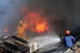 Petugas berusaha memadamkan gudang yang terbakar di Pesapen Kali, Surabaya, Jawa Timur, Kamis (6/7). Sebanyak 15 mobil pemadam kebakaran dikerahkan untuk memadamkan kebakaran yang meludeskan gudang alat-alat olahraga tersebut. Antara Jatim/Didik Suhartono/zk/17