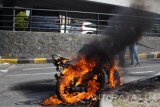 Sejumlah warga mencoba memadamkan api yang membakar motor yang terbakar di depan salah satu mall di Surabaya, Jawa Timur, Senin (10/7). Kebakaran tersebut diduga disebabkan oleh adanya arus pendek pada bagian kelistrikan mesin dan tidak ada korban jiwa dalam peristiwa itu. Antara Jatim/Umarul Faruq/zk/17