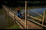 Warga berkendara di atas jembatan sesek bambu yang membelah Sungai Bengawan Solo di Desa Lengking, Bulu, Sukoharjo, Jawa Tengah, Minggu (16/7). Jembatan bambu yang menghubungkan Kecamatan Bulu dan Nguter tersebut digunakan masyarakat sekitar untuk mempersingkat jarak tempuh. ANTARA FOTO/Mohammad Ayudha/kye/17.