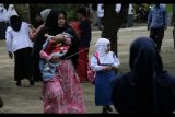 Seorang ibu berjalan sambil menggendong balitanya untuk mencari ruang belajar bagi anaknya yang baru pertama kali masuk sekolah di Yayasan Assyafiyah, Kendari, Sulawesi Tenggara, Senin (17/7). Sejumlah sekolah telah memulai kembali aktivitas belajar mengajarnya setelah libur panjang Lebaran. ANTARA FOTO/Jojon/ama/17.