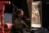 Dalang wayang beber khas Pacitan Rudhi Prasetyo mementaskan lakon Joko Kembang Kuning di area Simpang Lima Gumul Kediri, Jawa Timur, Minggu (16/7) malam. Lakon yang diambil dari Cerita Panji tersebut menampilkan 6 buah gulungan wayang dengan 24 adegan berdurasi satu jam. Antara Jatim/Prasetia Fauzani/zk/17