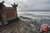 Seorang warga melintas di samping puing sebuah Pura yang tergerus ombak di Pantai Purnama, Gianyar, Kamis (27/7). Dinas Lingkungan Hidup Provinsi Bali mengidentifikasi 187 Km dari 430 Km garis pantai di Pulau Dewata mengalami abrasi akibat kenaikan air laut, perubahan arus laut dan beberapa bagian akibat ulah manusia. Antara Bali/Nyoman Budhiana/17.