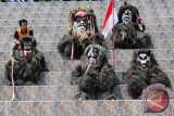 Seorang pria duduk bersama lima pemeran Amot dari Batang Tarang saat pembukaan Kongres Dayak Internasional 2017 di Rumah Radakng, Pontianak, Kalbar, Rabu (26/7). Amot dipercaya oleh Suku Dayak Taba Syam dari Desa Temiang Taba, Kecamatan Batang Tarang, Kabupaten Sanggau sebagai mahluk jahat pengganggu hasil panen masyarakat Dayak yang nantinya harus diusir dalam Ritual Nyeser. ANTARA FOTO/Jessica Helena Wuysang/17