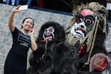 Seorang perempuan berfoto bersama dua pemeran Amot dari Batang Tarang saat pembukaan Kongres Dayak Internasional 2017 di Rumah Radakng, Pontianak, Kalbar, Rabu (26/7). Amot dipercaya oleh Suku Dayak Taba Syam dari Desa Temiang Taba, Kecamatan Batang Tarang, Kabupaten Sanggau sebagai mahluk jahat pengganggu hasil panen masyarakat Dayak yang nantinya harus diusir dalam Ritual Nyeser. ANTARA FOTO/Jessica Helena Wuysang/17