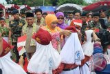 Menteri Sosial Khofifah Indar Parawansa membetulkan topi pelajar Sekolah Dasar yang menyambut kedatangannya di Lapangan Pahlawan Amuntai, dalam acara peluncuran penyaluran bantuan sosial non tunai Program keluarga Harapan (PKH). (Foto Antaranews Kalsel/hms/f)