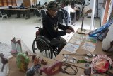 Seorang penyandang disabilitas yang juga pengusaha menyiapkan produk kerajinan hasil karyanya dalam pameran produk kegiatan pemberdayaan ekonomi bagi penyandang disabilitas di Sanur, Bali, Sabtu (29/7). Pelatihan kewirausahaan bidang konveksi, makanan, kerajinan dan elektronika tersebut melibatkan 65 penyandang disabilitas di seluruh Bali yang merupakan kegiatan awal dari program pelatihan terhadap 2.000 penyandang disabilitas di tujuh kota di Indonesia dalam dua tahun ke depan. Antara Bali/Nyoman Budhiana/2017.